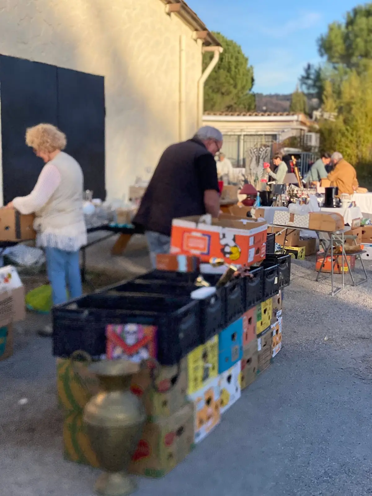 Des bénévoles installent les caisses et les tables du vide-grenier devant les locaux, au petit matin.
